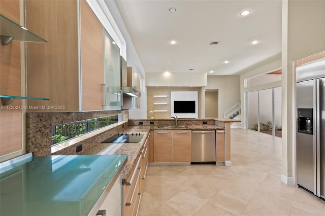 kitchen with light brown cabinets, stone counters, sink, appliances with stainless steel finishes, and kitchen peninsula