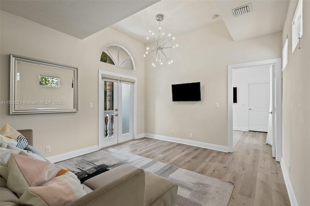 living room with a towering ceiling, light wood-type flooring, and a notable chandelier