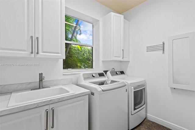 clothes washing area with cabinets, washing machine and dryer, and sink