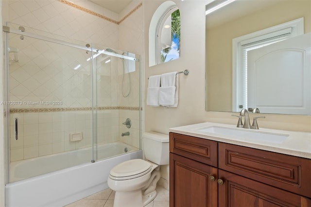 full bathroom with combined bath / shower with glass door, tile patterned floors, vanity, and toilet