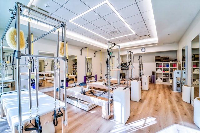 gym featuring hardwood / wood-style flooring and a raised ceiling