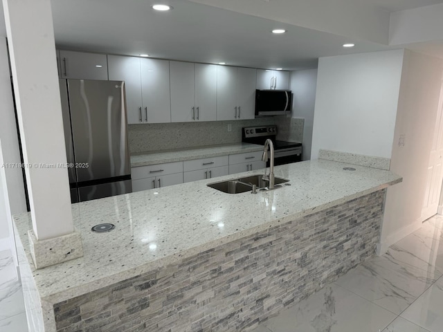 kitchen with kitchen peninsula, light stone countertops, backsplash, stainless steel appliances, and sink