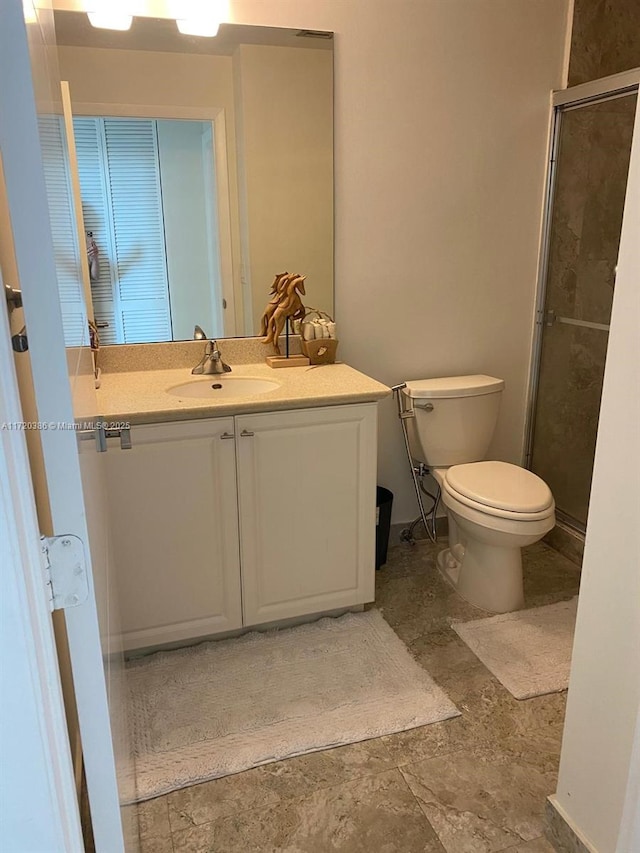 bathroom with vanity, toilet, and a shower with shower door