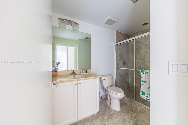 bathroom featuring a shower with door, vanity, and toilet