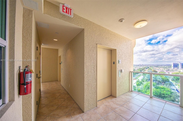 hallway with elevator and light tile patterned floors