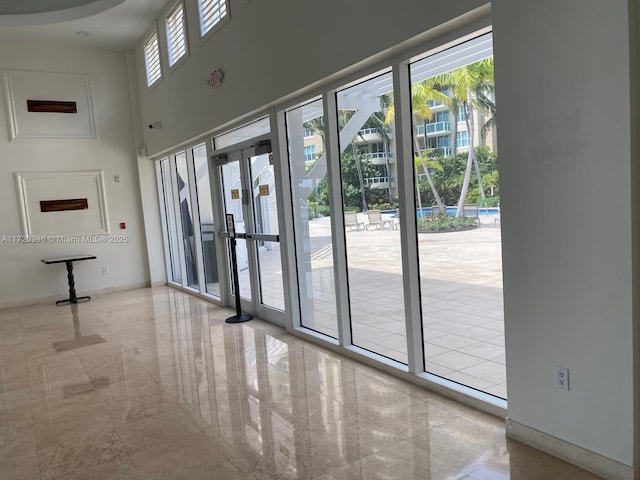 doorway to outside featuring plenty of natural light, a towering ceiling, and french doors