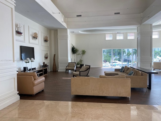 living room with a towering ceiling, decorative columns, and light hardwood / wood-style flooring