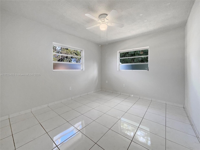 tiled empty room featuring a textured ceiling and ceiling fan