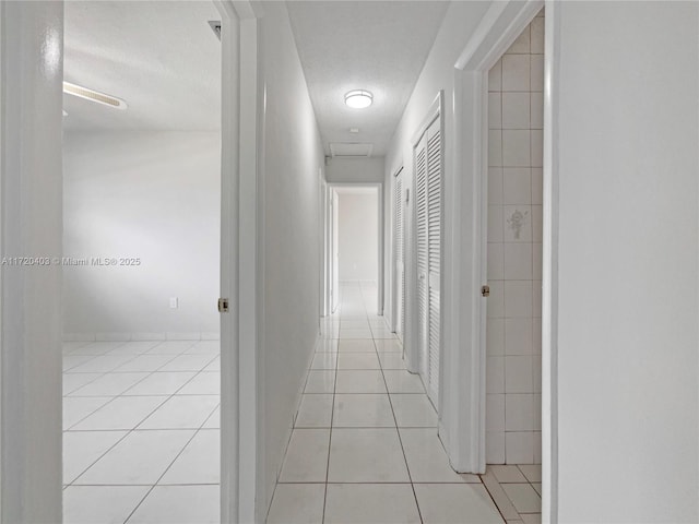 corridor featuring light tile patterned floors and a textured ceiling