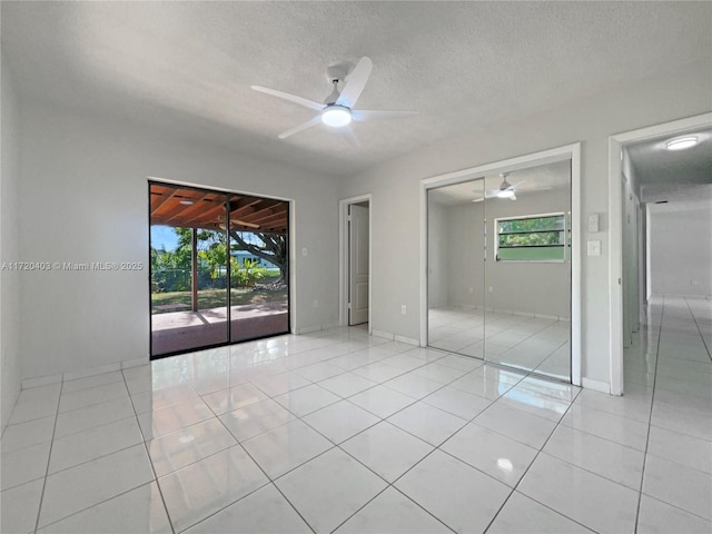 unfurnished bedroom with light tile patterned floors, a textured ceiling, access to outside, and ceiling fan