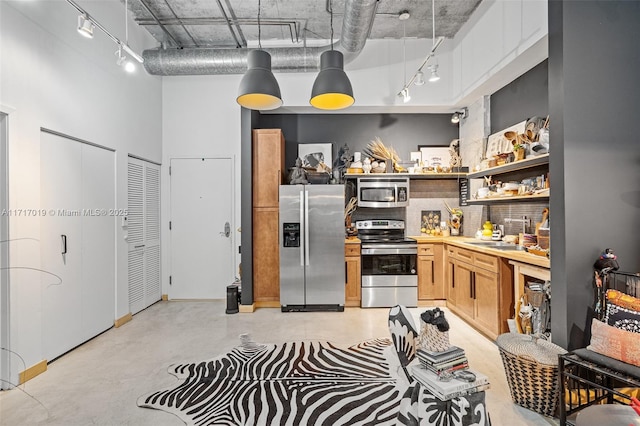 kitchen with decorative light fixtures, sink, stainless steel appliances, and a high ceiling