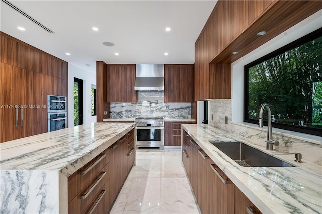 kitchen featuring light stone countertops, sink, wall chimney range hood, decorative backsplash, and appliances with stainless steel finishes