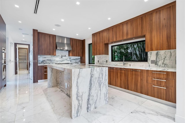 kitchen featuring light stone countertops, wall chimney range hood, sink, and tasteful backsplash