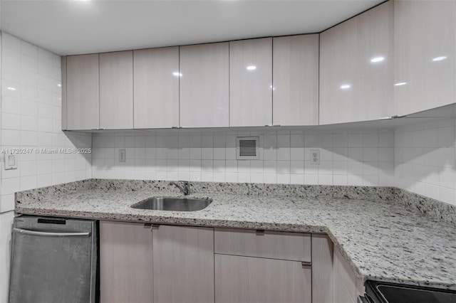 kitchen with dishwasher, decorative backsplash, light stone counters, and sink