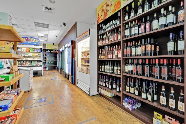 wine room with a drop ceiling and light wood-type flooring