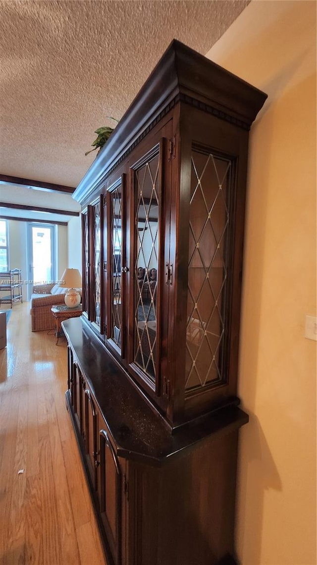 hall featuring a textured ceiling and light hardwood / wood-style floors