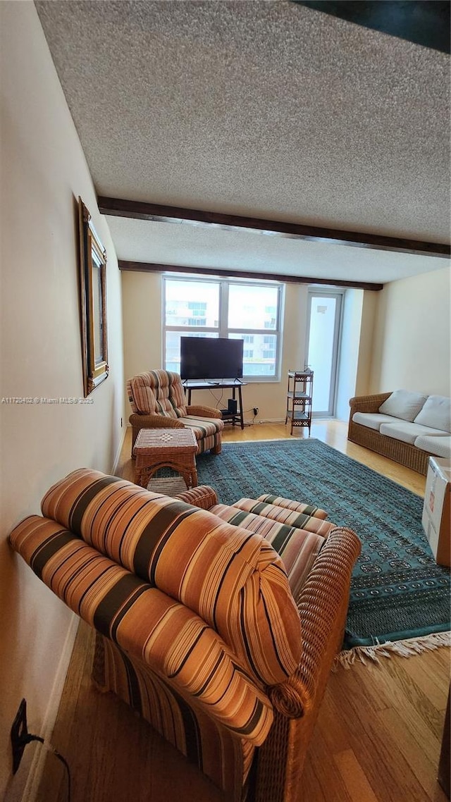 living room with beam ceiling, hardwood / wood-style floors, and a textured ceiling