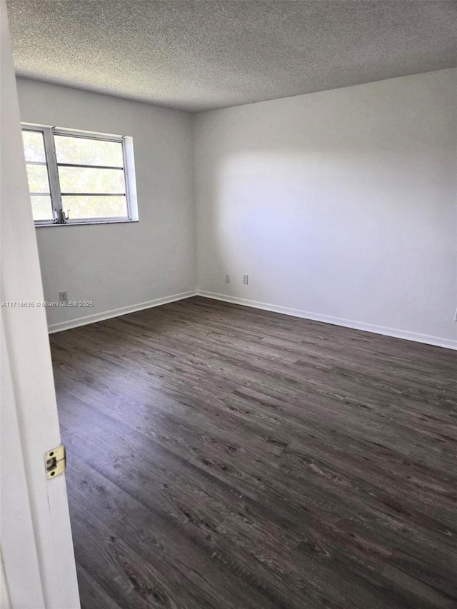 spare room featuring a textured ceiling and dark hardwood / wood-style flooring