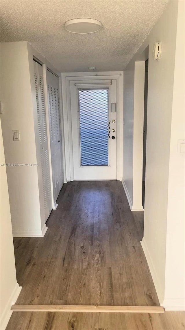 corridor with dark hardwood / wood-style flooring and a textured ceiling