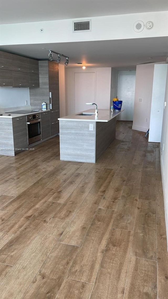 650 NE 32nd St Unit 1805, Miami, FL 33137 - kitchen featuring oven, modern cabinets, dark wood-type flooring, track lighting, and light countertops