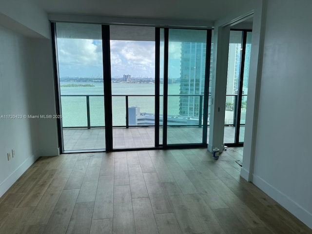650 NE 32nd St Unit 1805, Miami, FL 33137 - spare room with a wall of windows, wood finished floors, and a water view