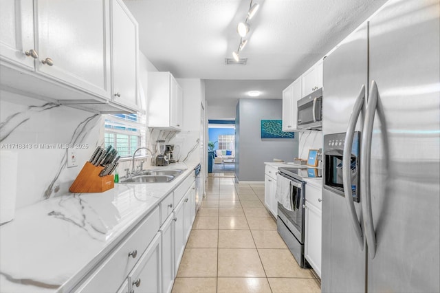 kitchen featuring white cabinets, appliances with stainless steel finishes, light tile patterned floors, and sink