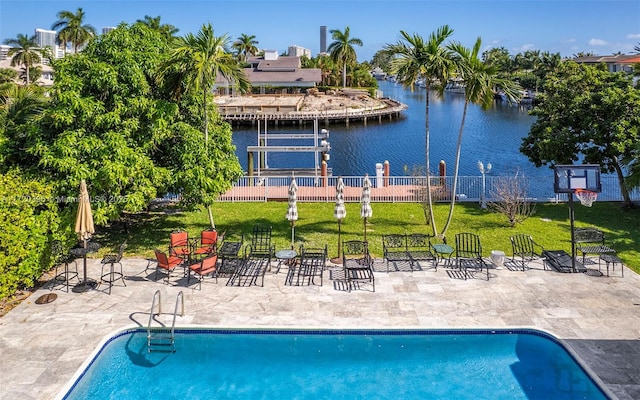 view of pool featuring a lawn, a water view, and a patio