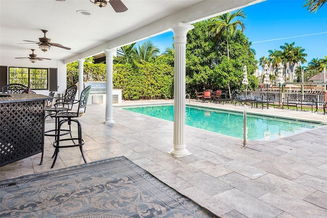 view of swimming pool with a patio area, ceiling fan, and exterior kitchen