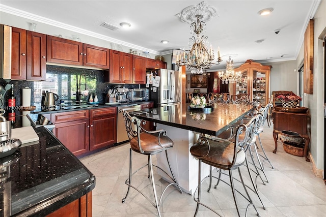 kitchen featuring stainless steel appliances, crown molding, decorative light fixtures, an inviting chandelier, and a center island