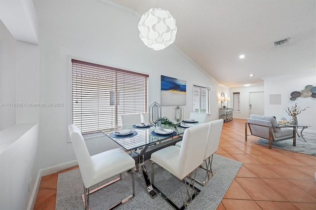 tiled dining space with ornamental molding and lofted ceiling