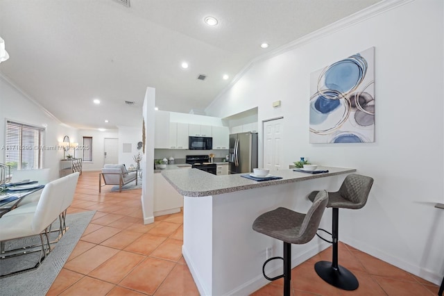 kitchen featuring black appliances, a kitchen breakfast bar, kitchen peninsula, vaulted ceiling, and white cabinetry