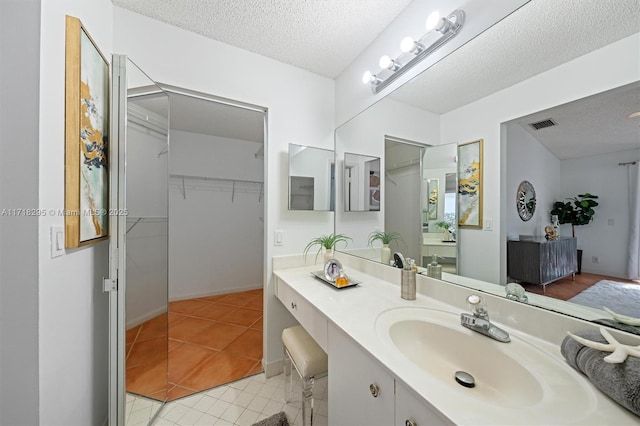 bathroom with a textured ceiling, vanity, and tile patterned floors