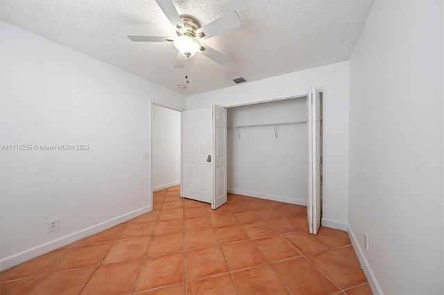 unfurnished bedroom with light tile patterned floors, a textured ceiling, a closet, and ceiling fan