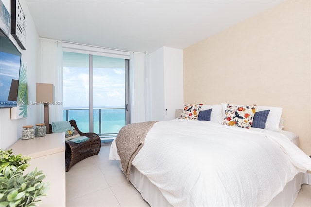 bedroom with a water view, light tile patterned floors, and a wall of windows