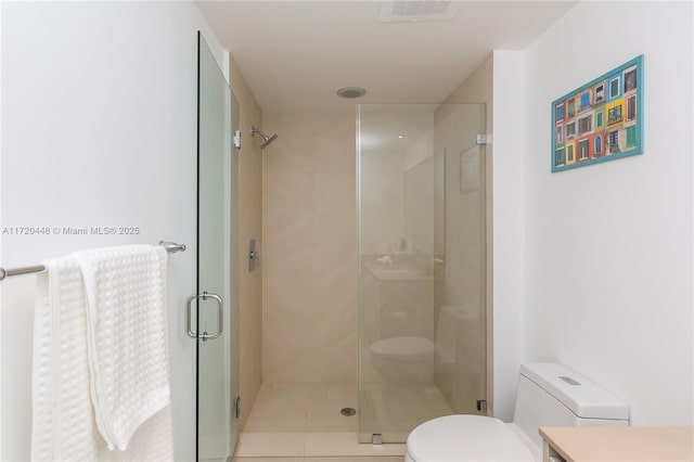 bathroom with tile patterned floors, toilet, and a shower with shower door