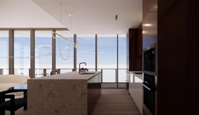 kitchen featuring wood-type flooring, a water view, oven, and sink