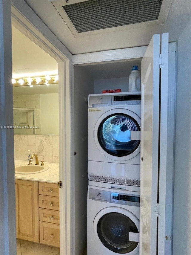 washroom featuring sink, light tile patterned floors, and stacked washer / drying machine