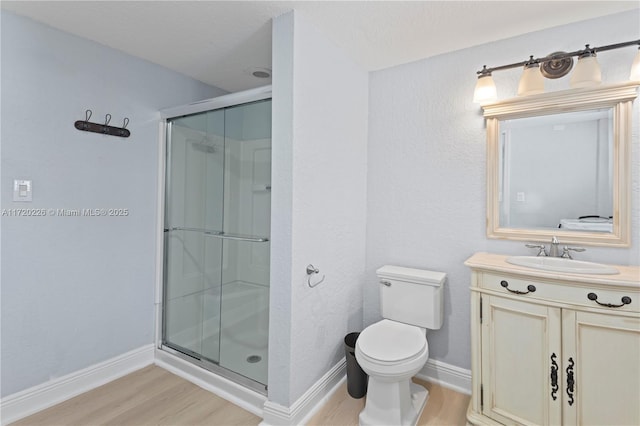 bathroom with hardwood / wood-style flooring, vanity, toilet, and walk in shower