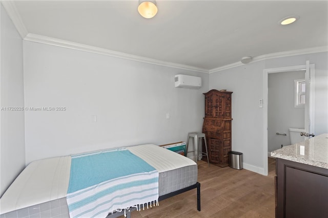 bedroom with a wall unit AC, wood-type flooring, and ornamental molding