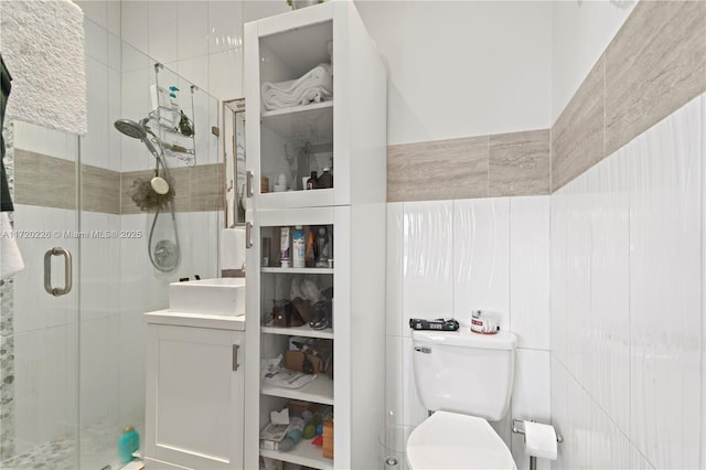 bathroom featuring vanity, a shower with door, toilet, and tile walls