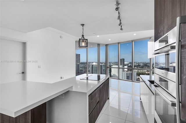 kitchen with expansive windows, black electric cooktop, pendant lighting, light tile patterned floors, and a kitchen island