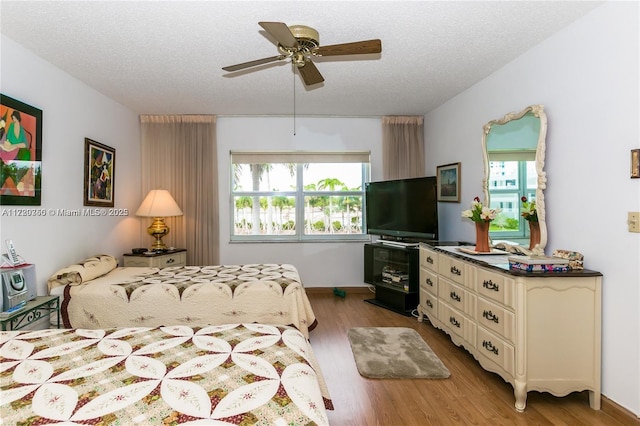 bedroom featuring ceiling fan, light hardwood / wood-style floors, a textured ceiling, and multiple windows