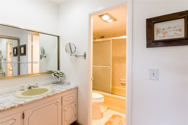 full bathroom featuring vanity, bath / shower combo with glass door, and toilet