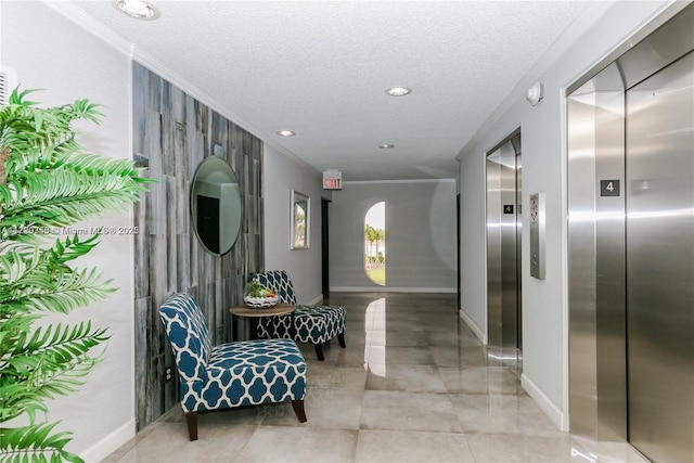 corridor with crown molding, a textured ceiling, and elevator