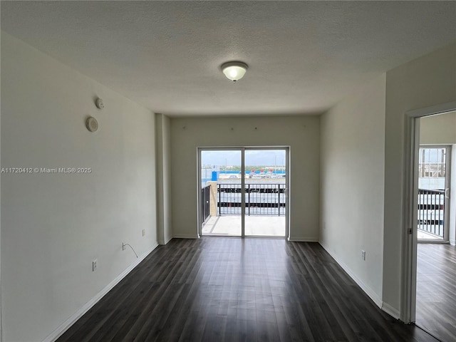 spare room with a textured ceiling and dark wood-type flooring