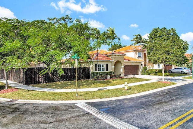 mediterranean / spanish home featuring a garage and a front yard