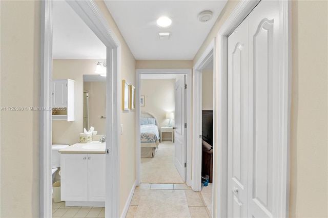 corridor featuring light tile patterned floors and sink