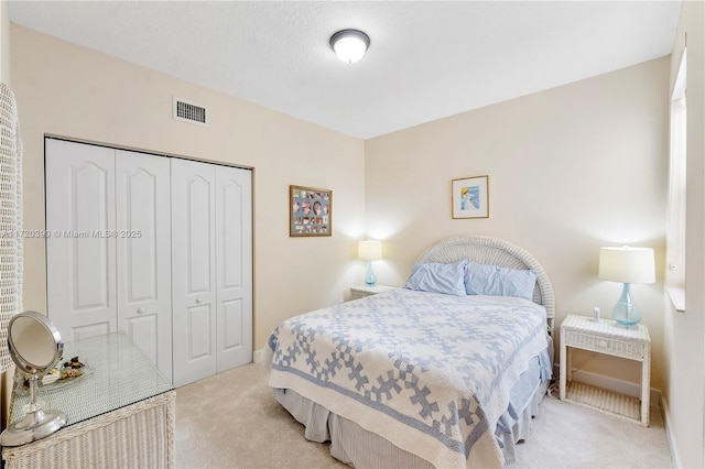 bedroom featuring light carpet, a textured ceiling, and a closet