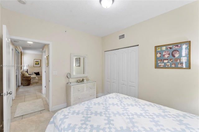 tiled bedroom with a textured ceiling and a closet