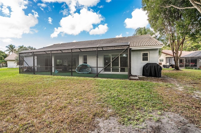 rear view of property featuring a lawn and glass enclosure